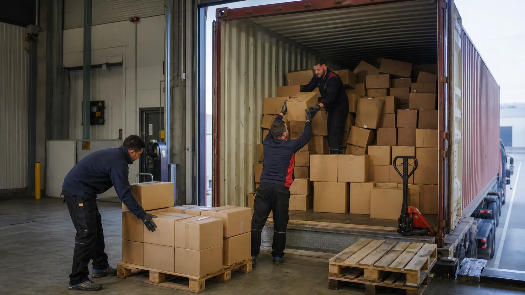 Team van SAM Logistics Support lost losse dozen uit een geopende zeecontainer en palletiseert de goederen